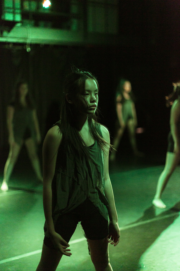 Bella mid-performance with the dance company, lit in green