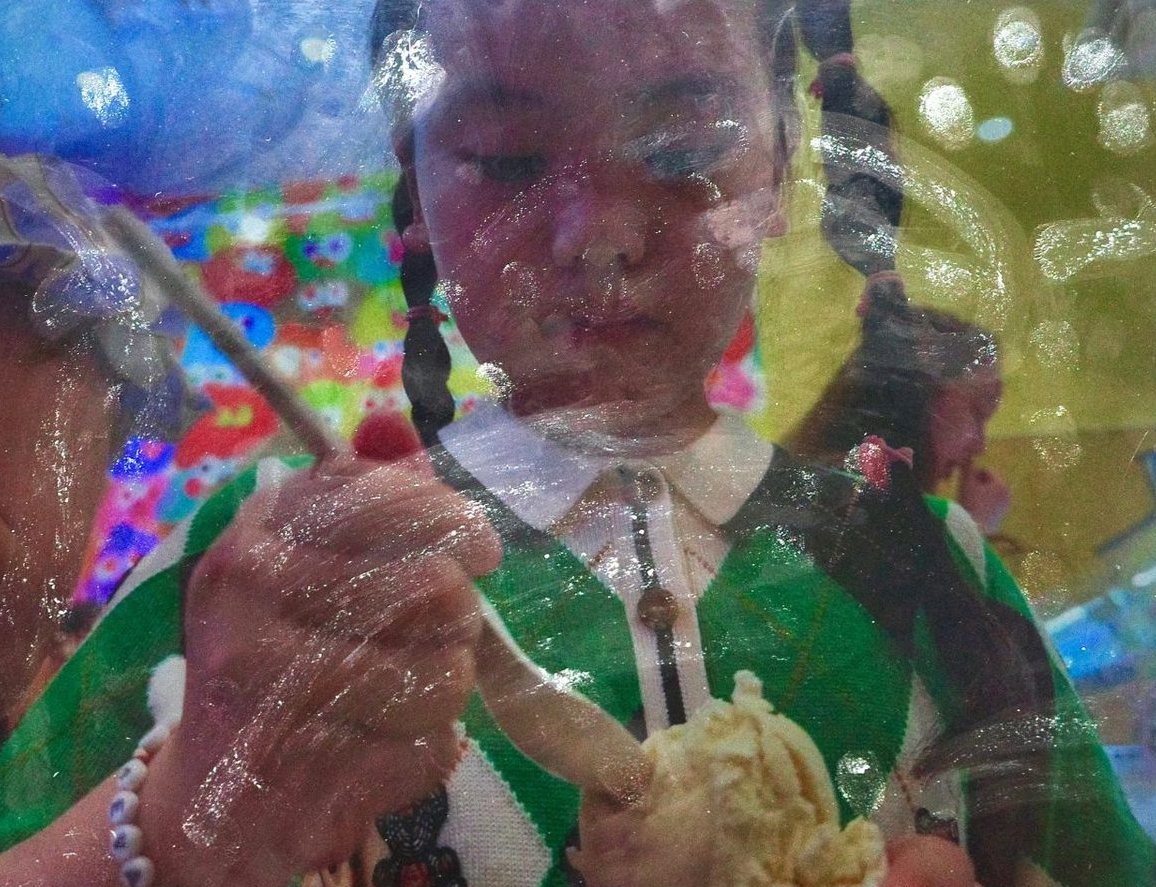 AP Photography: a girl with ice cream seen through painted glass